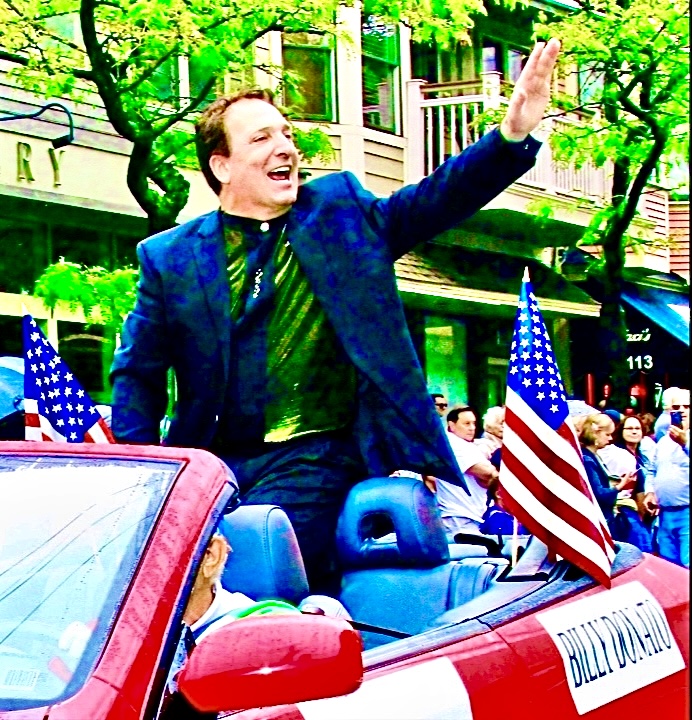 Billy Donato as Grand Marshal, waving from a convertible in a parade